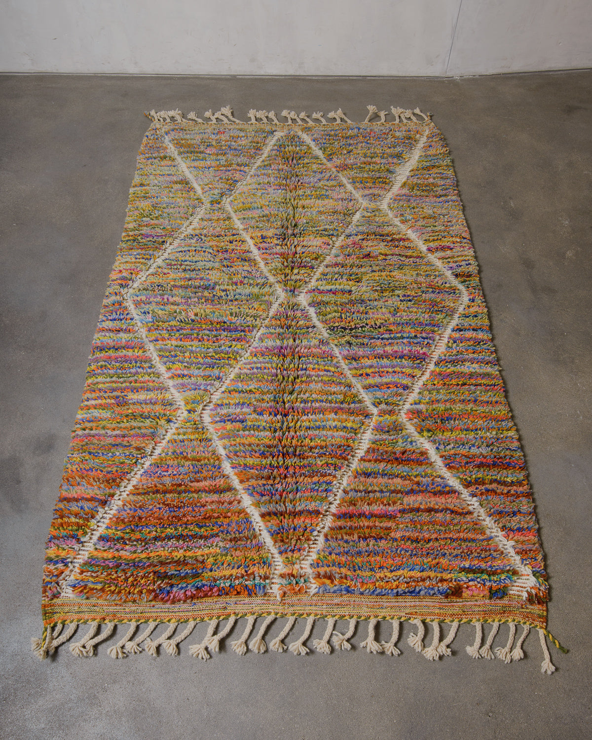 Multicoloured wool rug on a plain floor.